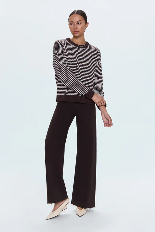 Woman wearing a striped sweater and black pants on a white background