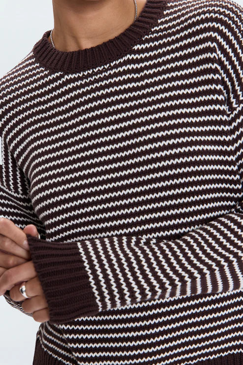 Close-up of a black and white striped sweater with brown trim.