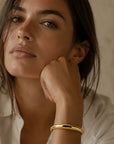 Woman wearing a gold bracelet with a neutral background