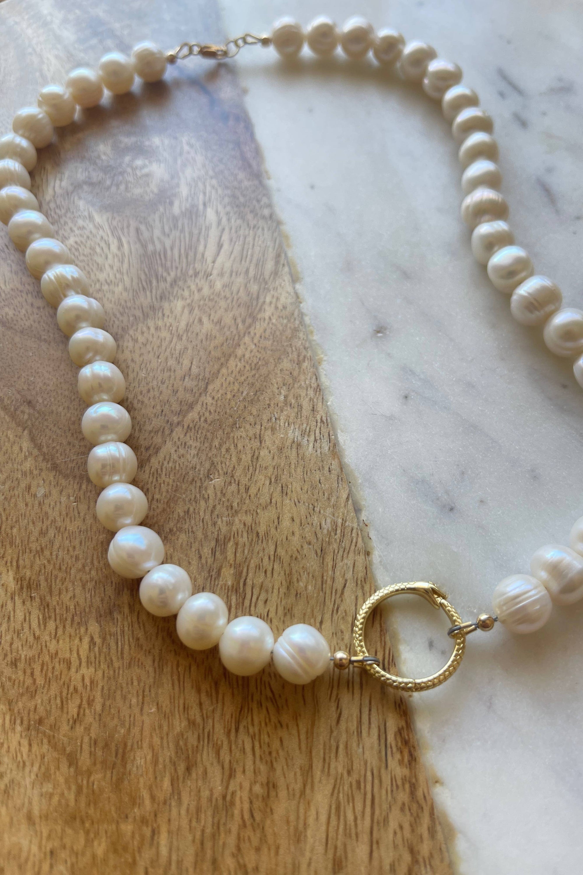 Pearl necklace with a gold clasp on a marble surface