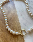Pearl necklace with a gold clasp on a marble surface