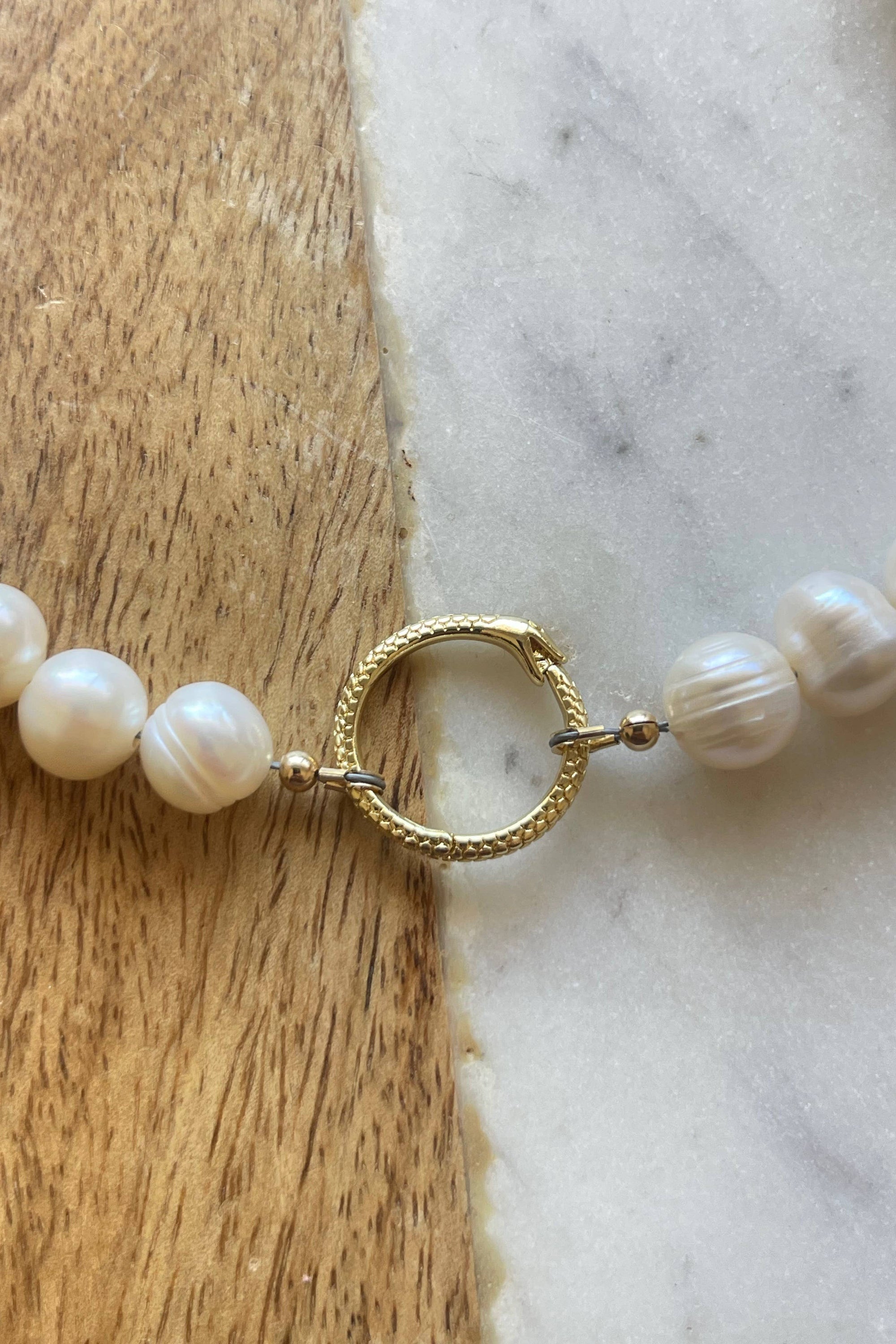 Pearl necklace with a gold clasp on a marble surface