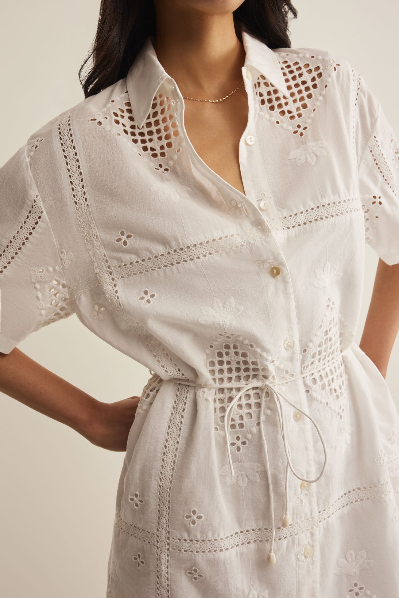 White dress with intricate cut-out patterns on a neutral background