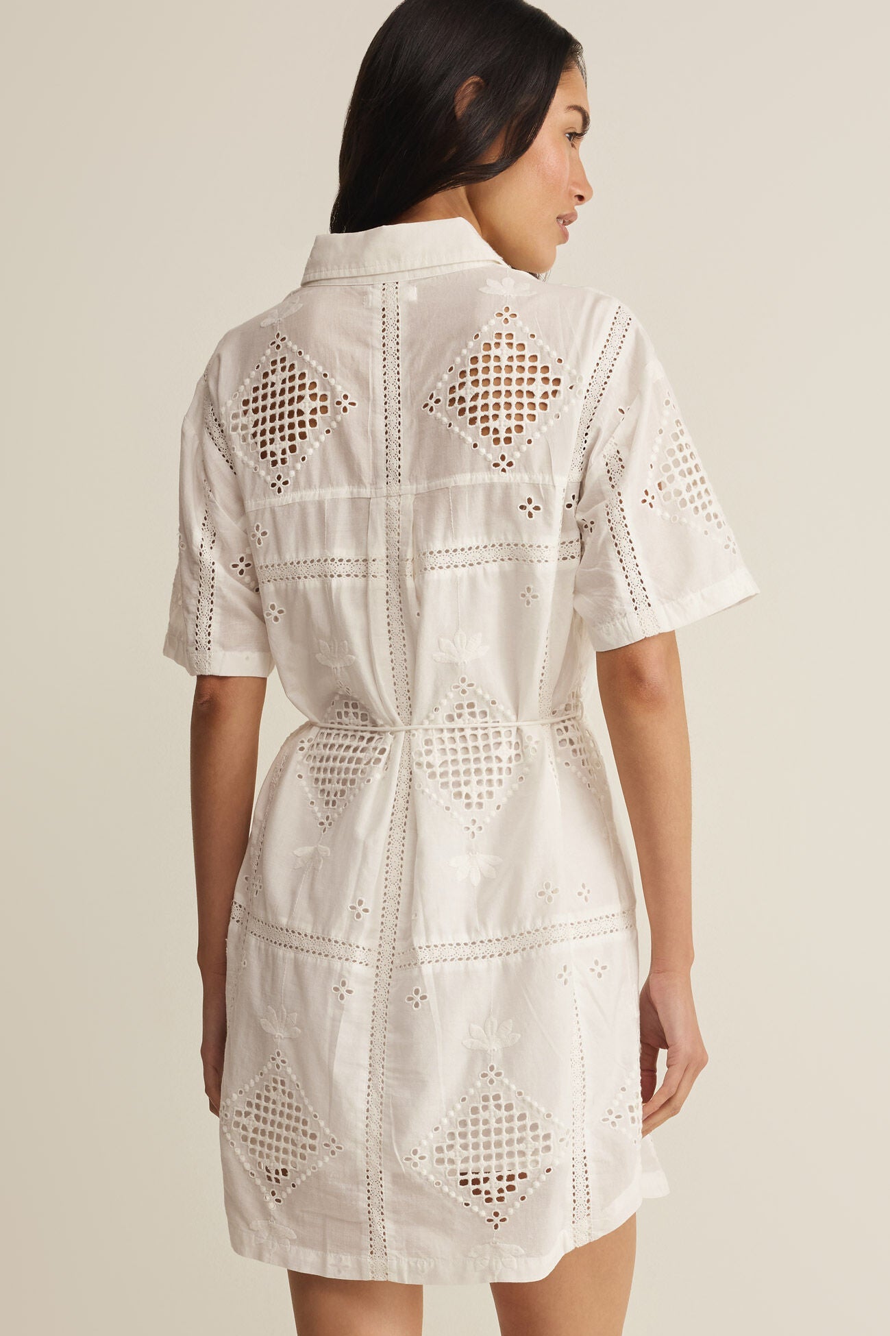 Woman wearing a white lace dress against a neutral background
