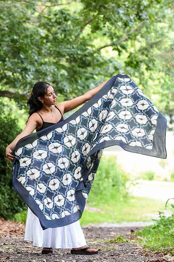Woman holding a large floral-patterned fabric in a natural setting
