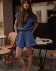 Woman in a blue outfit standing in an outdoor cafe setting