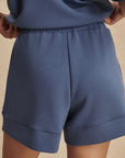 Blue shorts worn by a person on a beige background