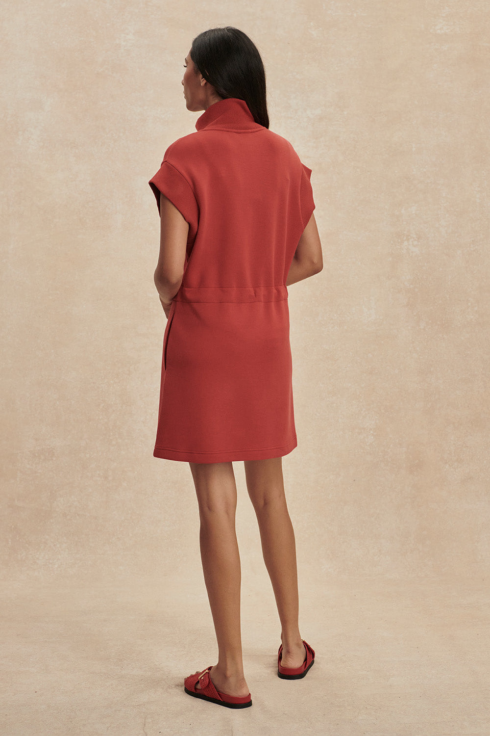 Woman wearing a red dress against a beige background