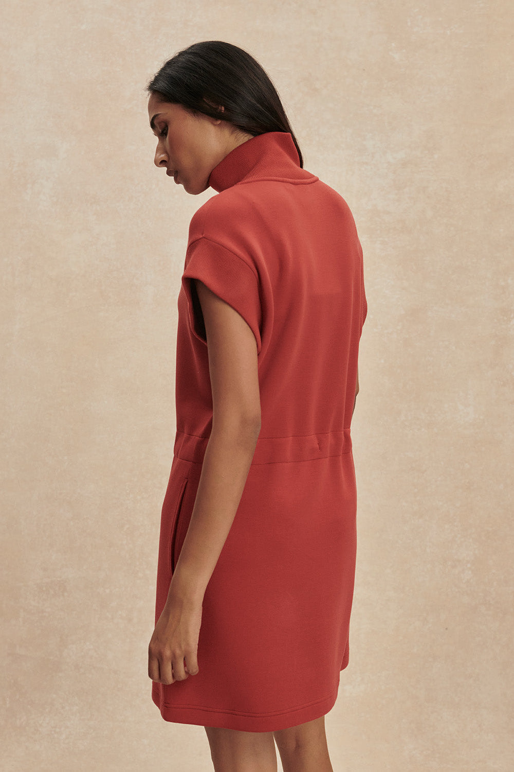 Woman wearing a red dress against a beige background