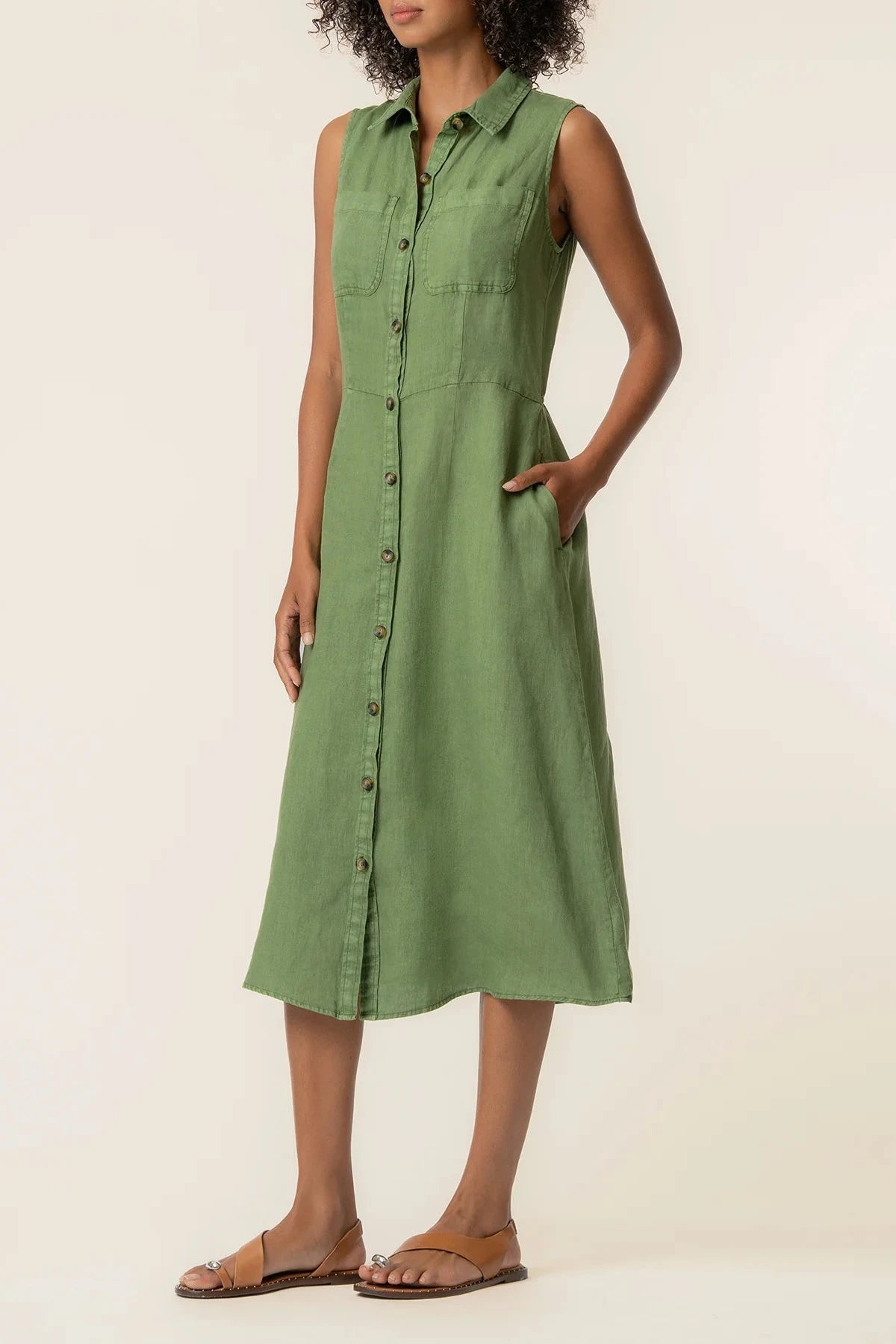 Woman wearing a green sleeveless dress against a plain background