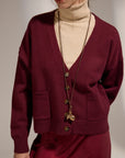 Person wearing a burgundy cardigan over a beige turtleneck with a plain background