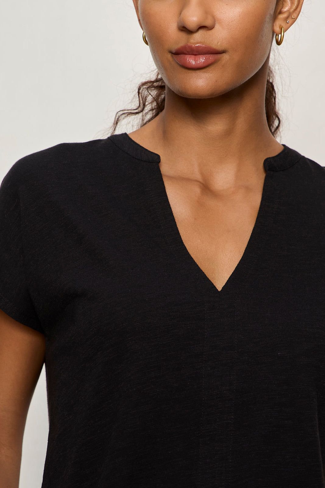 Woman wearing a black V-neck t-shirt against a plain background
