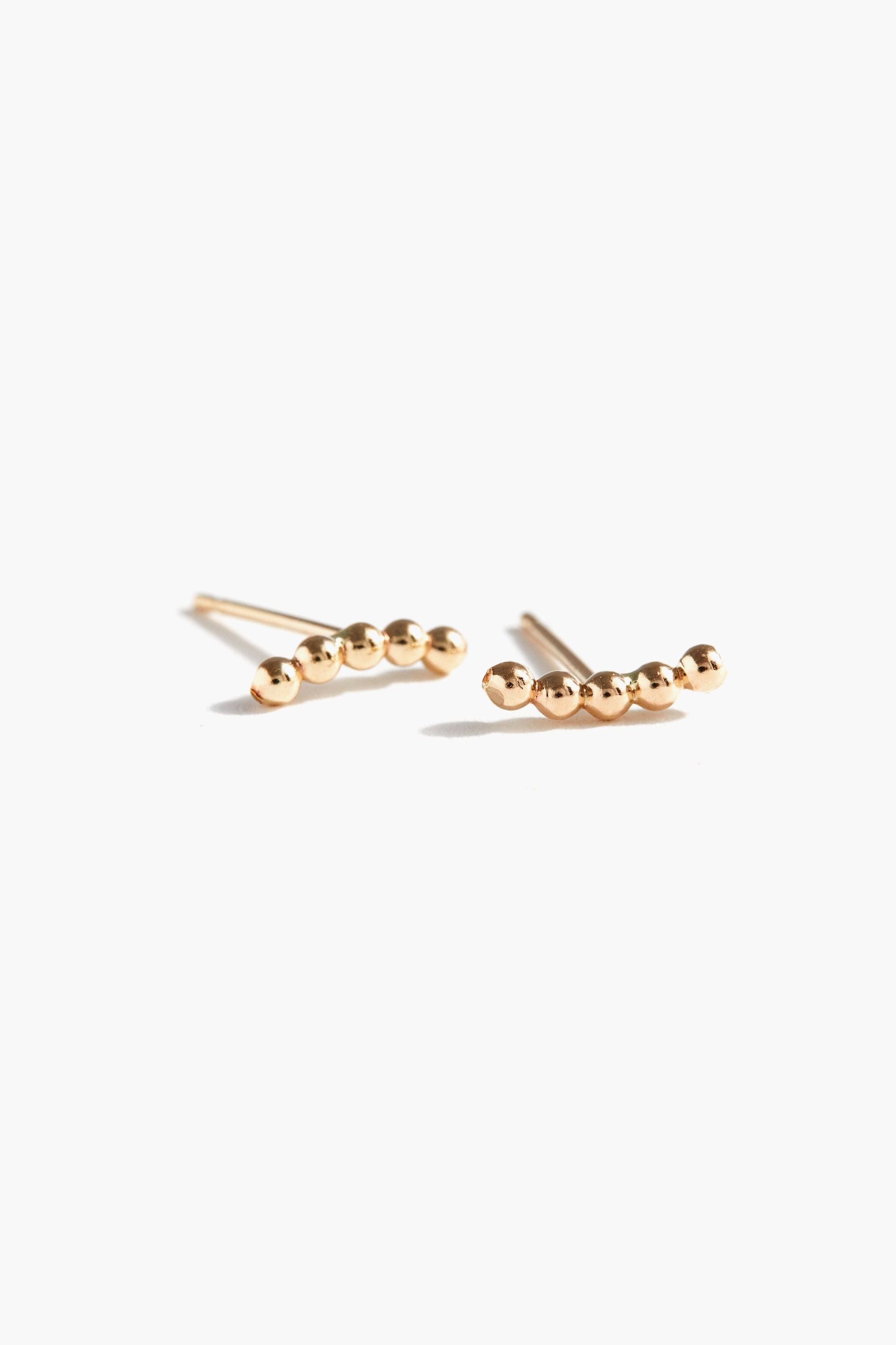 A pair of gold-filled stud earrings with a series of small gold balls aligned in a line on each earring.