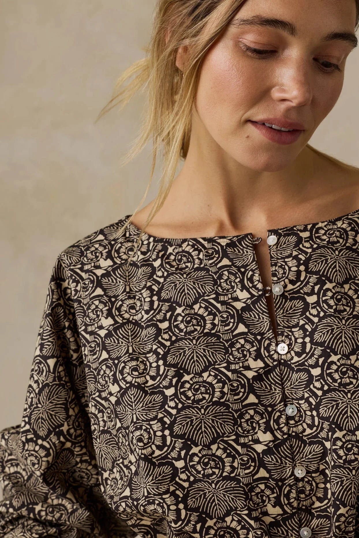 Woman wearing a black and white patterned top against a beige background
