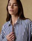 Woman wearing a blue and white striped shirt against a beige background