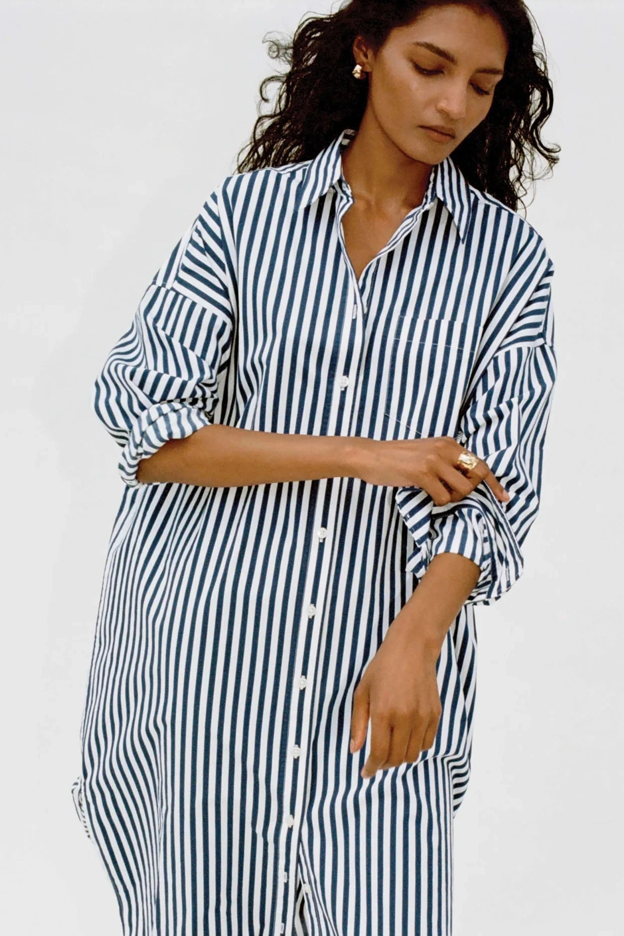 Woman wearing a blue and white striped dress against a plain background