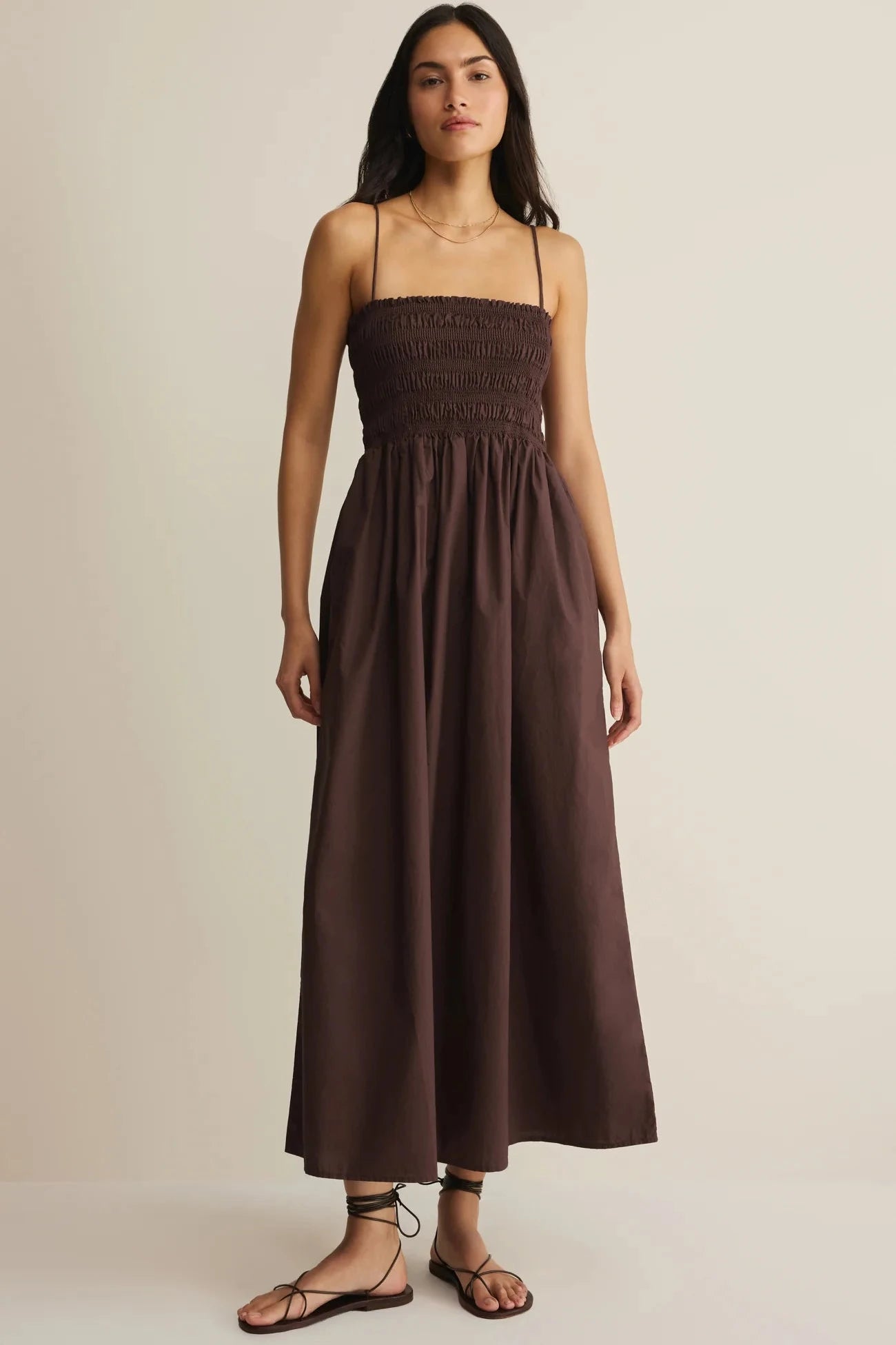 Woman wearing a brown dress against a beige background