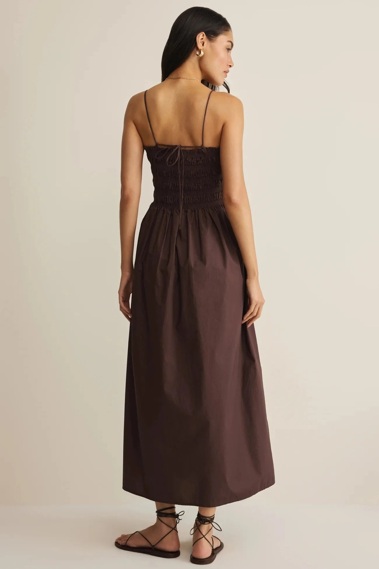 Woman wearing a brown dress against a beige background