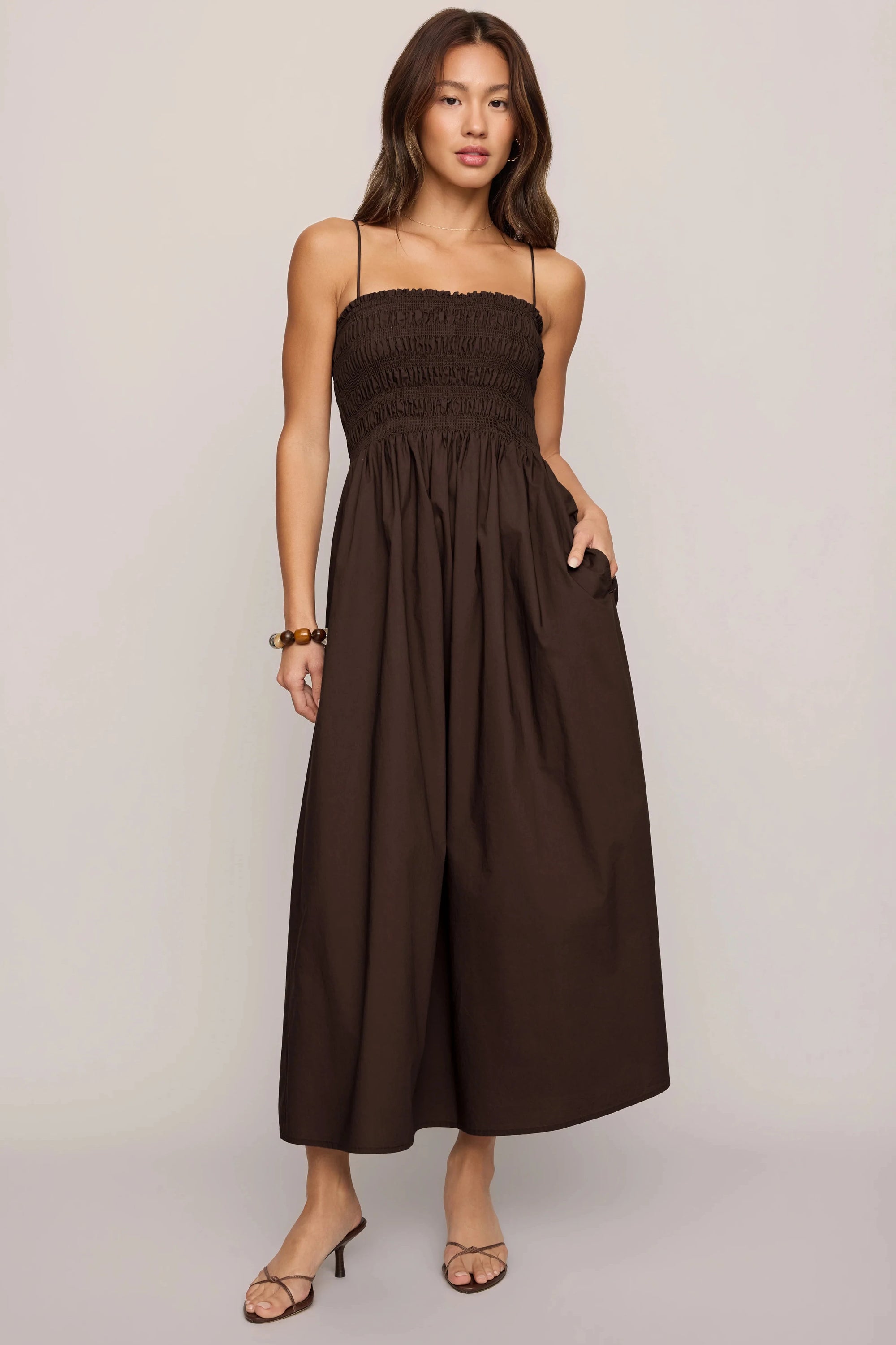 Woman wearing a brown strapless dress against a plain background