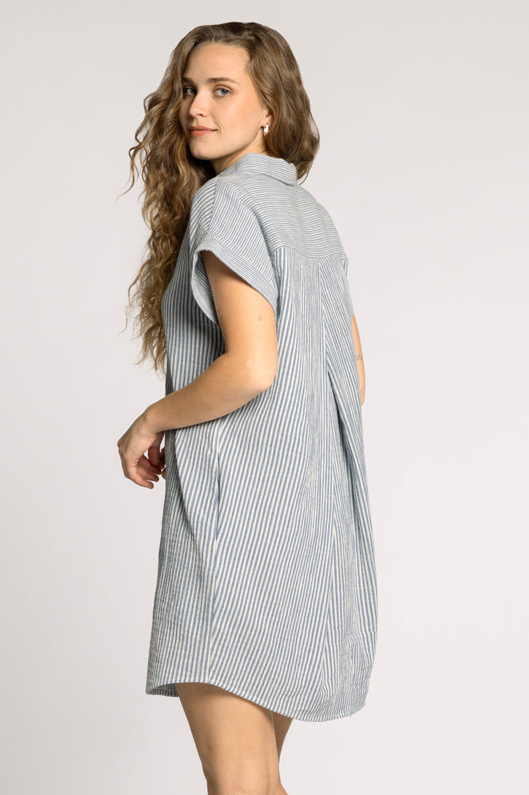 Woman wearing a gray striped dress and brown knee-high boots on a white background