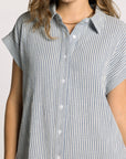 Woman wearing a short-sleeve, button-up shirt with a blue and white striped pattern on a plain background.