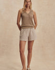 Woman wearing a sleeveless top and shorts on a beige background