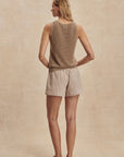 Woman wearing a sleeveless top and shorts on a beige background