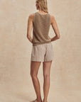 Woman wearing a sleeveless top and shorts on a beige background