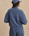 Person wearing a blue tracksuit and cap on a beige background