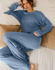 Woman wearing a blue ribbed lounge set on a bed