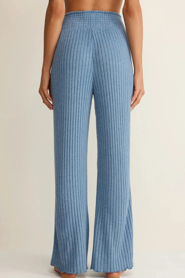 Blue ribbed pants worn by a person on a beige background