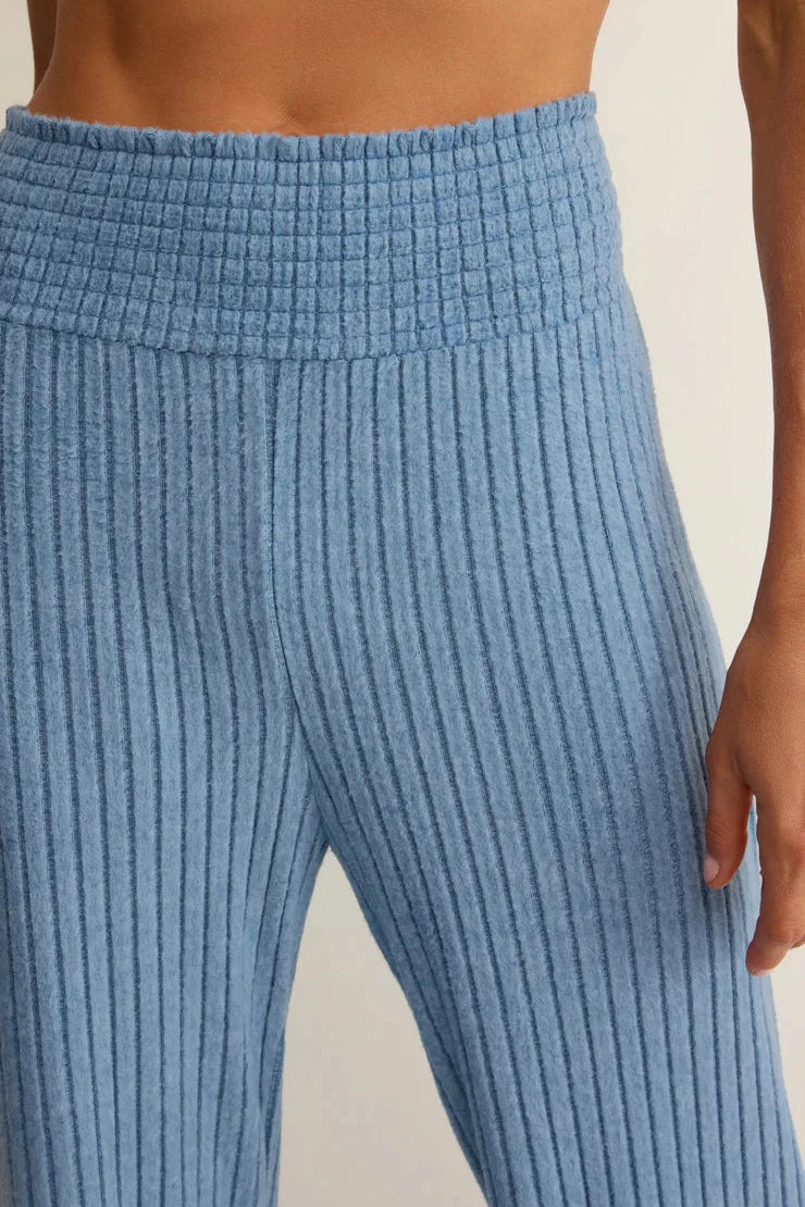 Close-up of blue ribbed pants on a neutral background