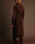 Person wearing a brown coat and pants against a matching background