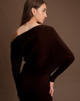 Woman wearing a dark brown off-shoulder dress against a brown background