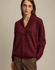 Woman wearing a burgundy sweater against a beige background
