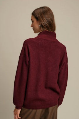Person wearing a burgundy sweater against a beige background