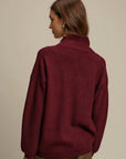 Person wearing a burgundy sweater against a beige background
