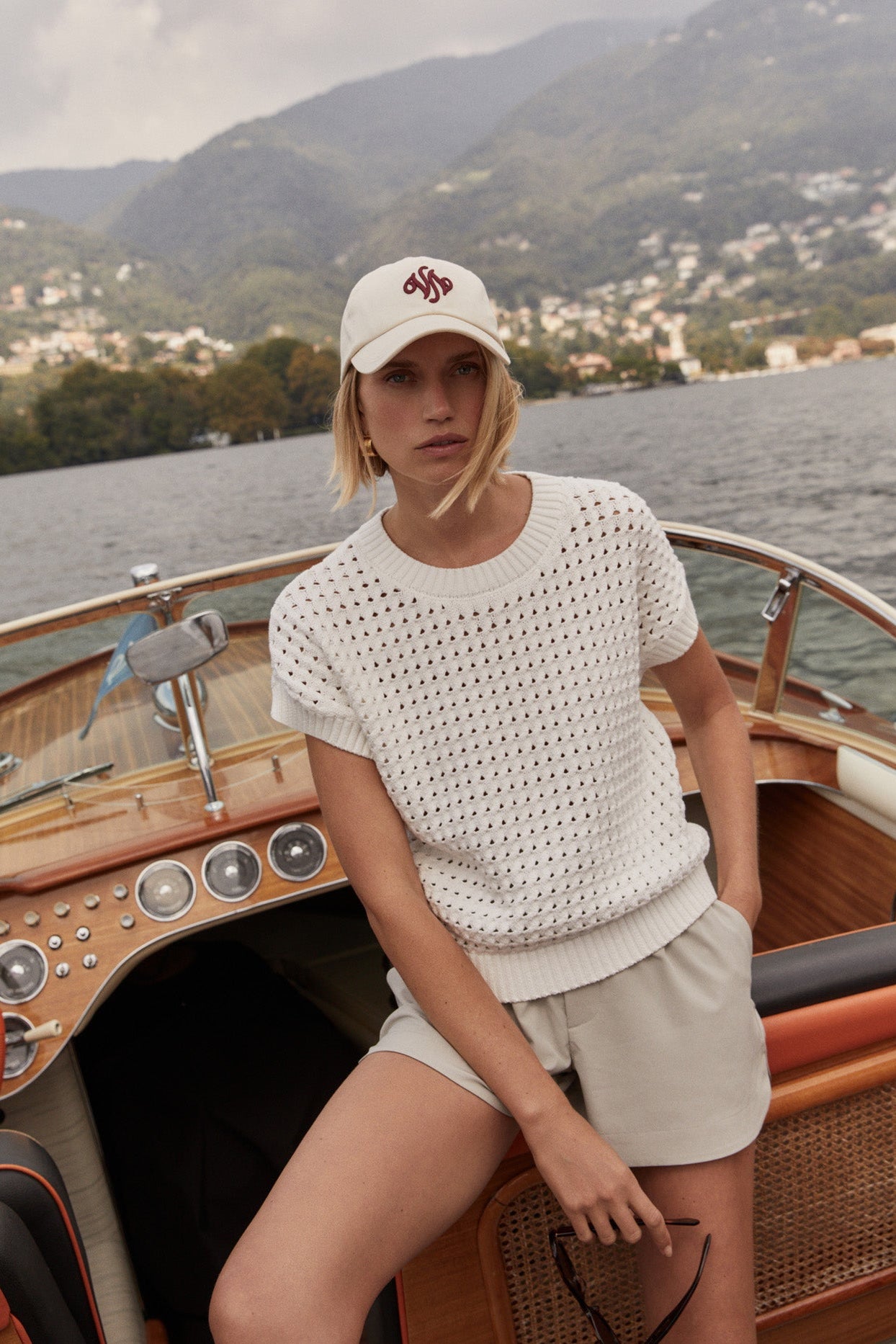 Woman on a boat wearing a white textured top and beige shorts with a scenic background.