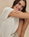 Woman wearing a white knit top against a beige background
