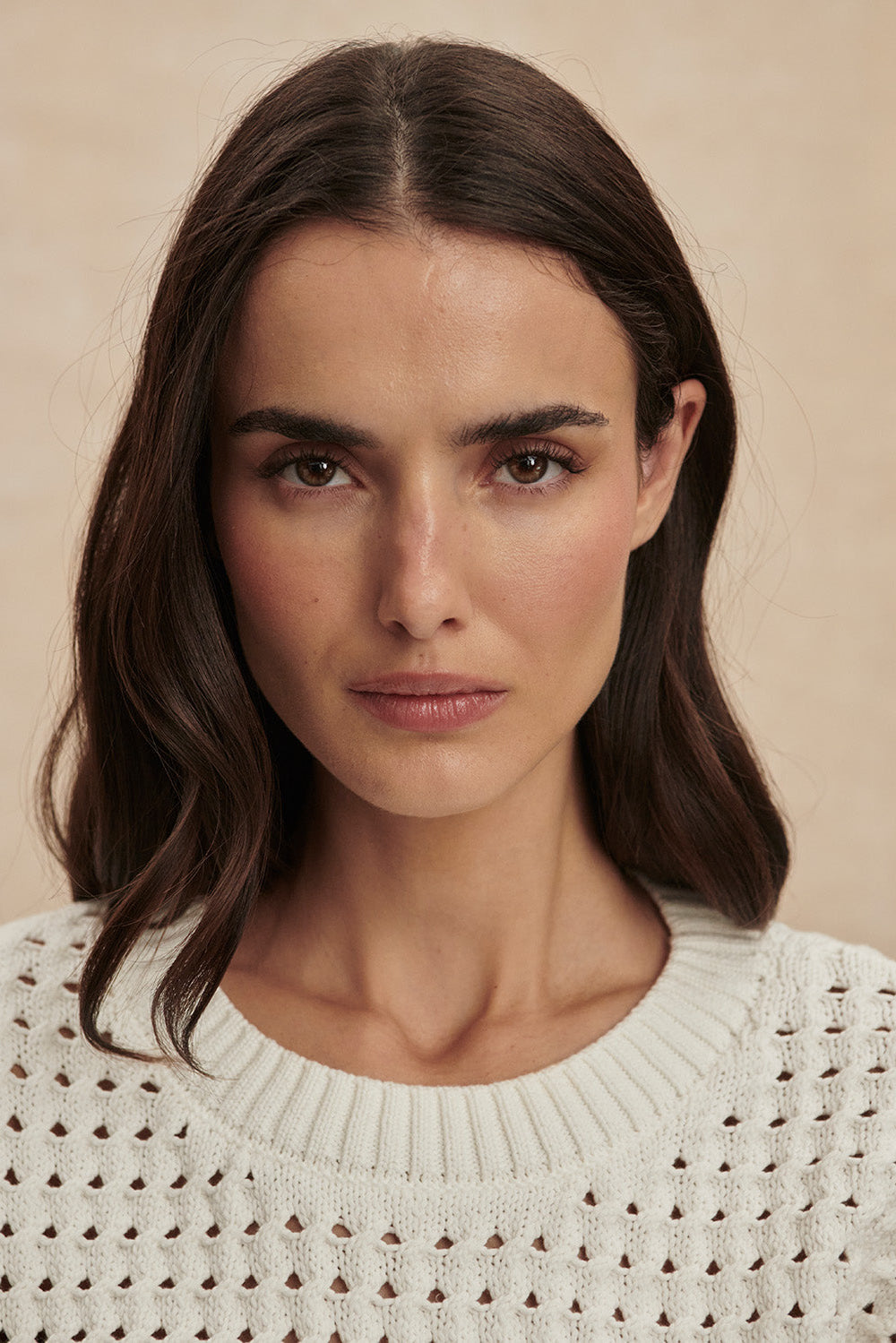 Woman wearing a white textured sweater against a beige background