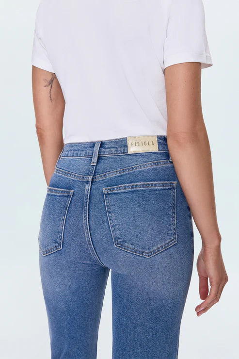 Person wearing blue jeans with a visible brand label on a white background