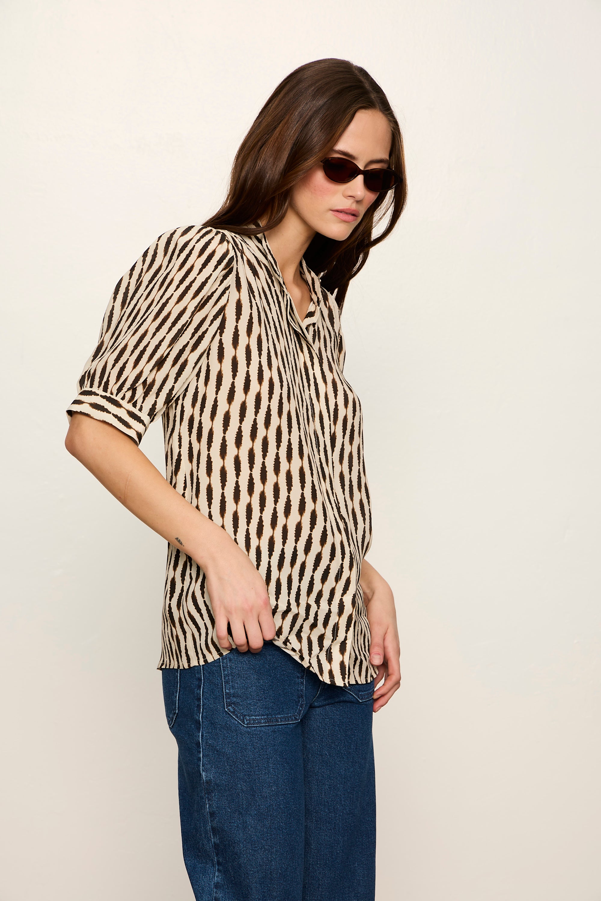 Woman wearing a leopard print blouse and blue jeans against a plain background