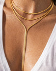 Gold body chain worn by a person with a white top