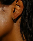 Close-up of an ear with a small hoop earring on a dark background