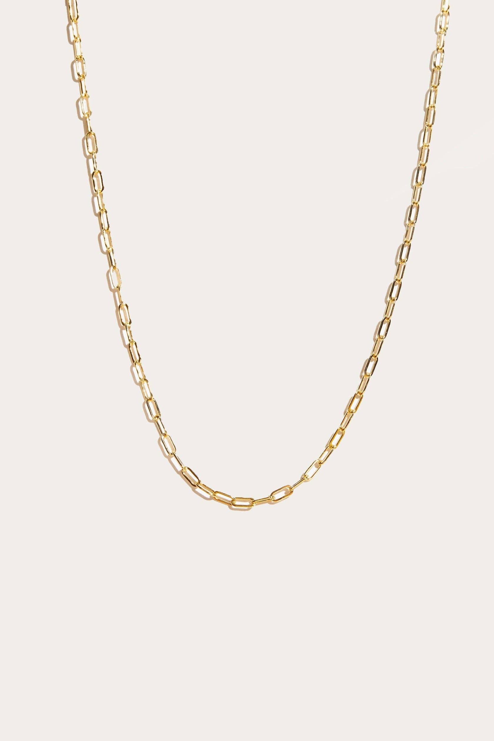Gold chain necklace on a light beige background