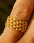 Gold ring on a person's finger with a blurred natural background