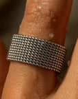 Silver textured ring on a finger with a blurred background