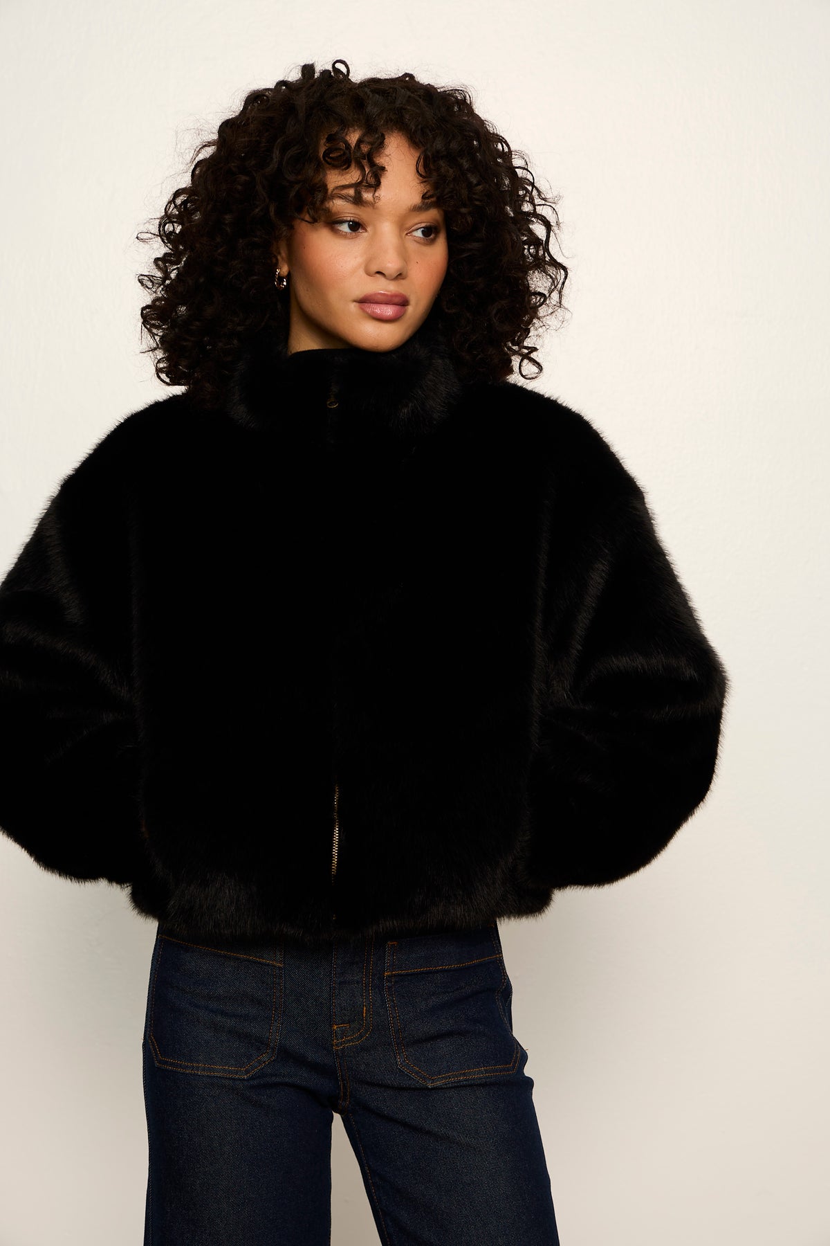 Person wearing a black fur coat against a white background