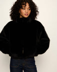 Person wearing a black fur coat against a white background