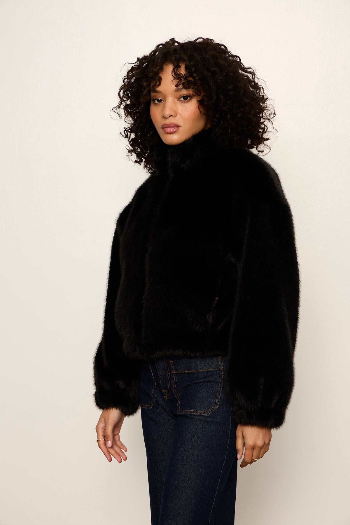 Woman wearing a black fur coat against a plain background